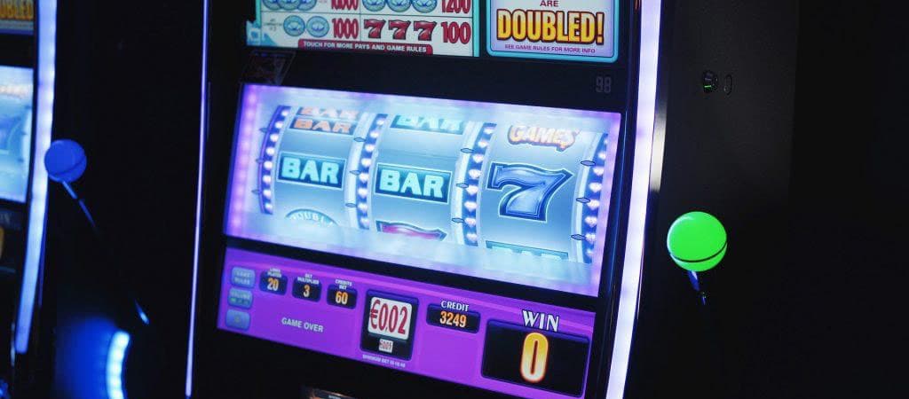 automat jednoręki bandyta, symbole BAR, cyfra 7, fioletowe podświetlenie, dźwignia, wyświetlacz kredytów, kasyno stacjonarne